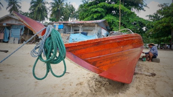nelayan memperbaiki kapal di pantai Nongsa